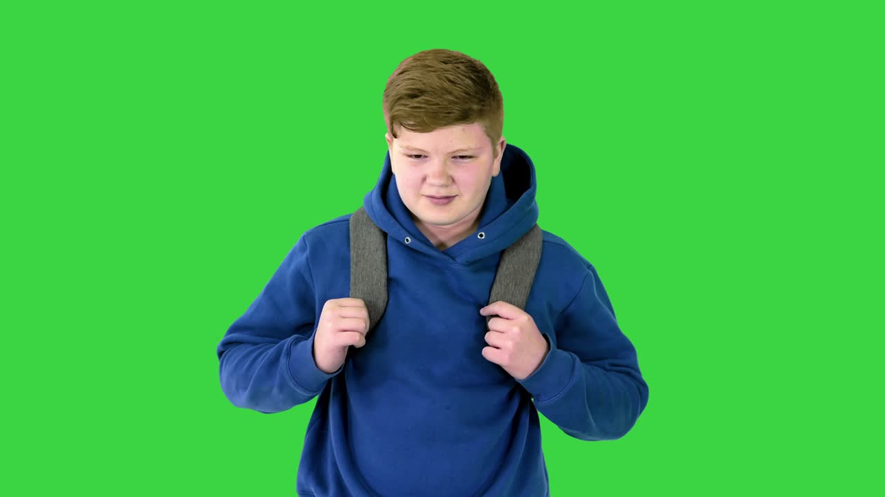 Cute schoolboy with backpack walking carefully on a Green Screen, Chroma Key