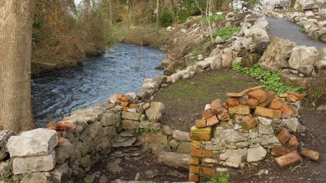 flowing river, a construction site with bricks, stones, and sand, vegetation, and an asphalt road