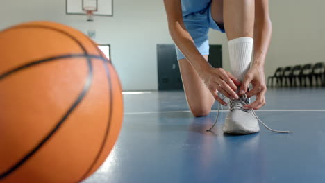 tying shoelaces, basketball player preparing for game on indoor court