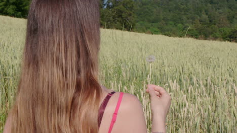 a woman blowing a dandelion outside in the green