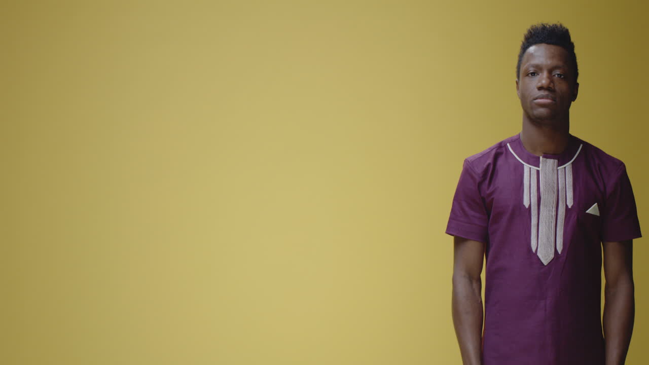 Happy African Man Pointing and Gesturing on Yellow Background