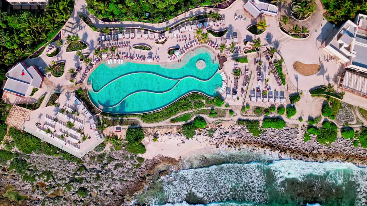 trs yucatan resort en tulum, méxico. una toma directa del mar caribe con grandes olas que se estrellan en la playa cerca de la piscina infinita.