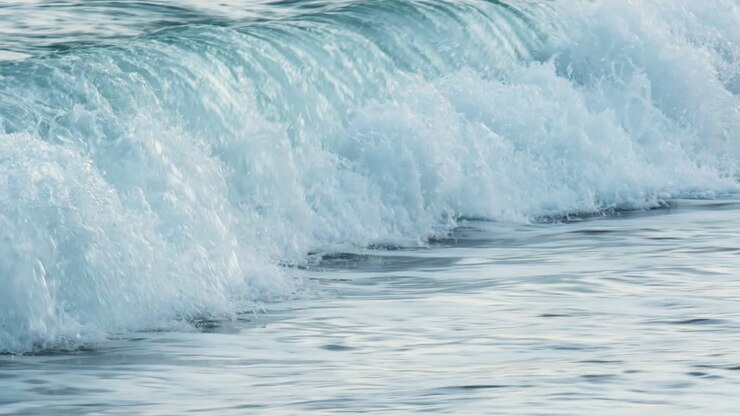 Zeitlupe von wunderschönen blauen Meerwasserwellen, die an einen tropischen Sandstrand schlagen.