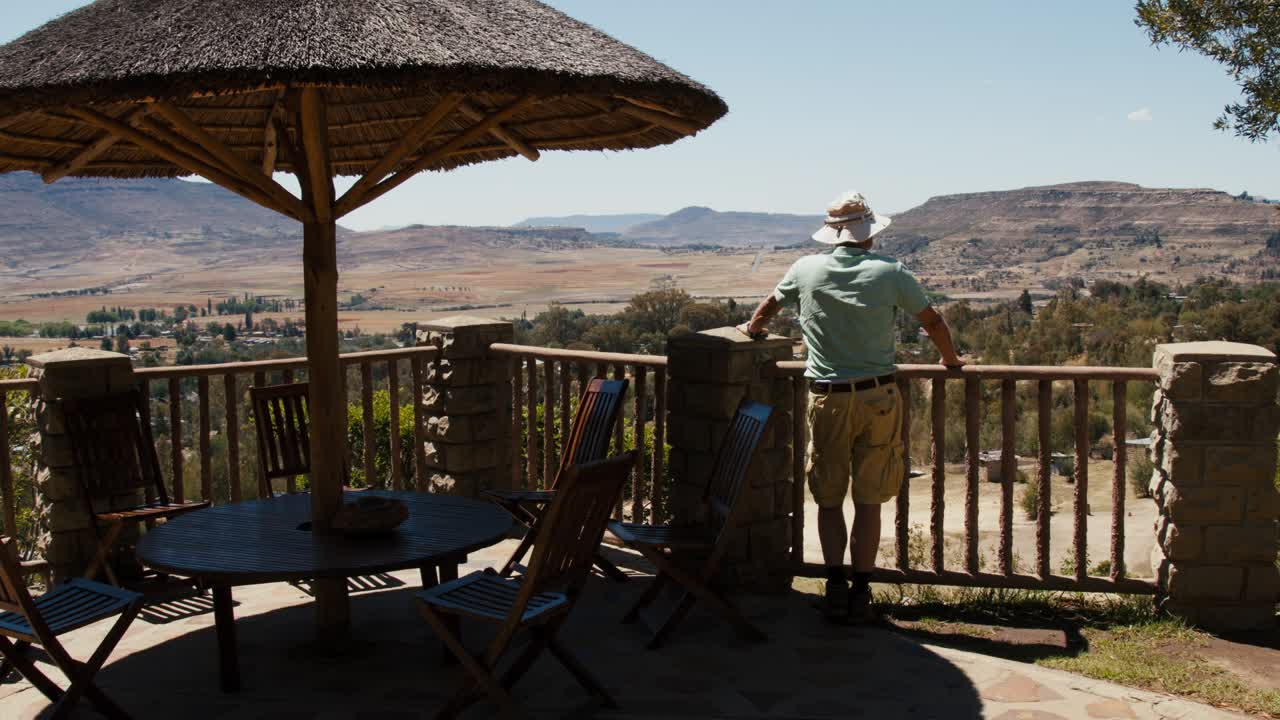 Old man standing on a viewing point looking out to a distanced scenery