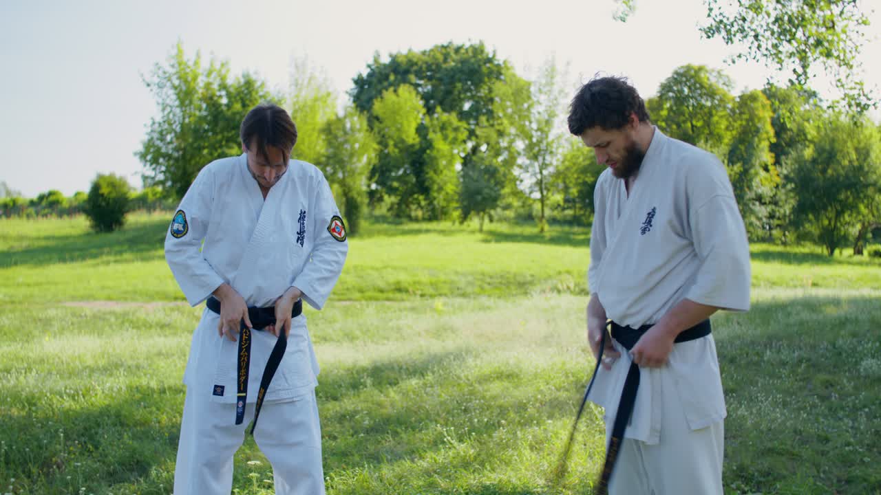 Men Tying Karate Belts Outdoors