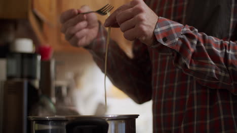 male adult tasting a pasta to see if it is cooked