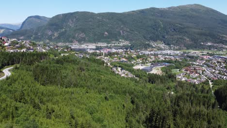 Sideways-moving-aerial-of-FÃ¸rde-and-FÃ¸rdefjorden-sea-from-a-distance---Watching-road-and-forest-with-panoramic-city-overview