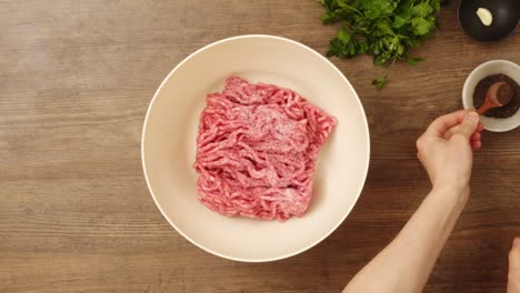 crop person adding spices to ground meat