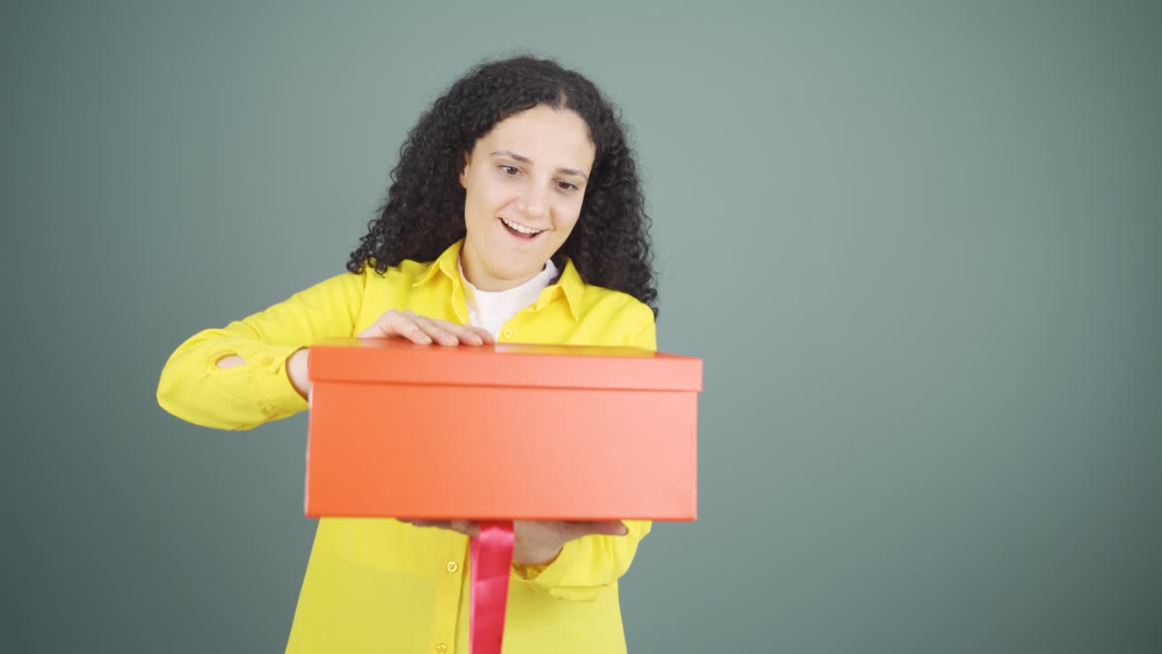 una joven feliz y alegre abriendo un paquete de regalos.