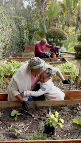 happy african american grandmother and granddaughter embracing in sunny garden, slow motion