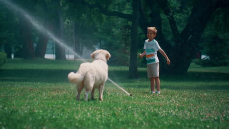 Kleiner-Junge-Spielt-Wassersprinkler-Auf-Der-Grünen-Wiese-Mit-Verspieltem-Golden-Retriever