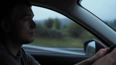 man driving a car in the rain