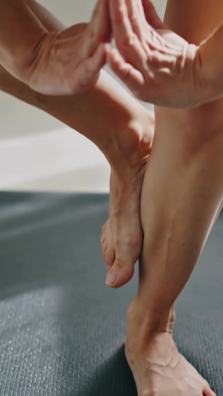 Vertical video: Pressing toes, man lifting foot, joining hands to balance on mat at home, barefoot