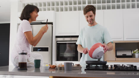 video de una feliz pareja diversa preparando el desayuno juntos en la cocina