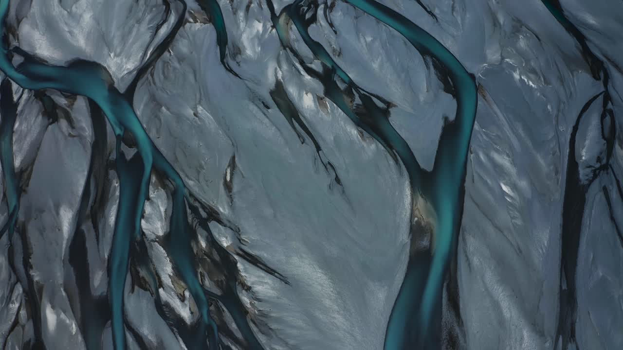 Top down drone shot of Blue Glacial Braided River delta weaving through vast gray valley, Tasman River, New Zealand, South Island