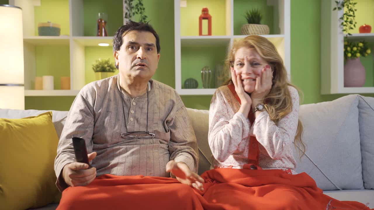 La coppia anziana che guarda la TV sta guardando brutte notizie sullo schermo ed è turbata