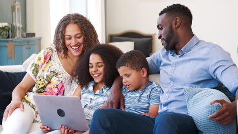 Zeitlupenaufnahme-Einer-Familie,-Die-Auf-Dem-Sofa-Sitzt-Und-Sich-Einen-Film-Ansieht,-Der-Auf-Dem-Laptop-Gestreamt-Wird