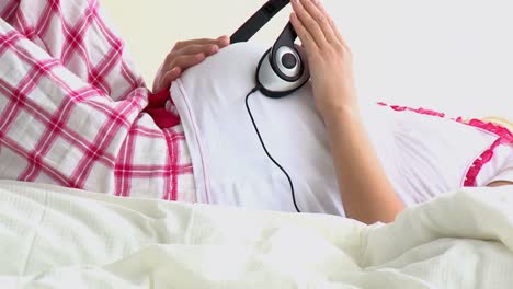 Close-up-of-a-pregnant-using-headphones-on-her-belly