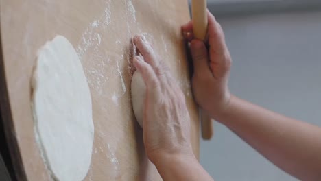 hands preparing dough with a rolling pin