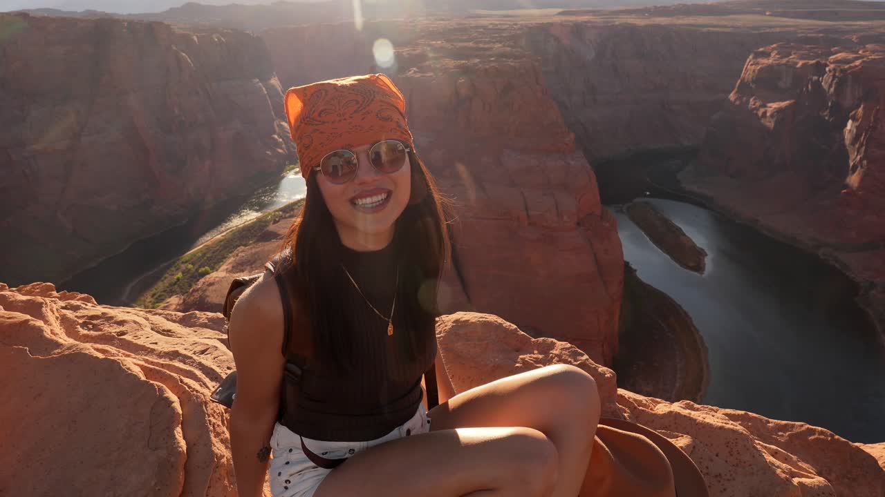 Donna felice che sorride sul bordo di una scogliera con vista su Horseshoe Bend