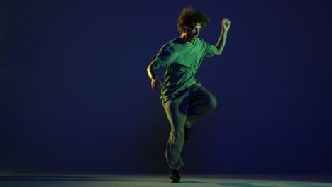 stylish young man, hip-hop dancer dancing isolated over dark blue background in neon light. modern dance art, fashion, youth, ad, style. 4k, video
