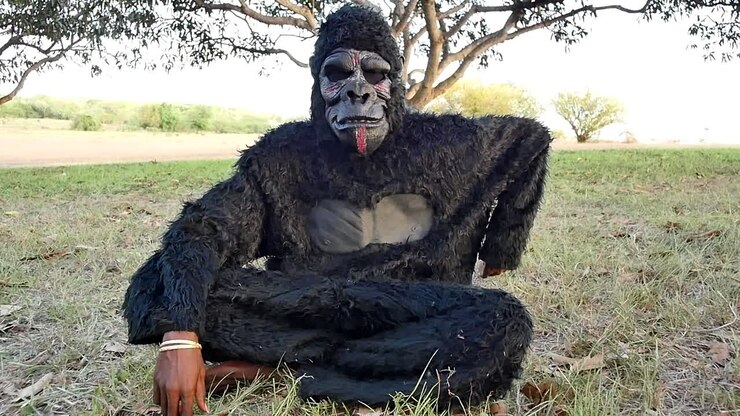 Skræmmende sort gorillakostume, stor hvid kniv stikker i jorden