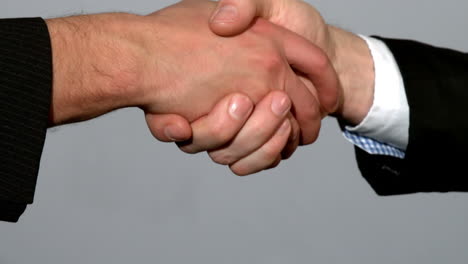 hombres estrechando la mano sobre un fondo gris