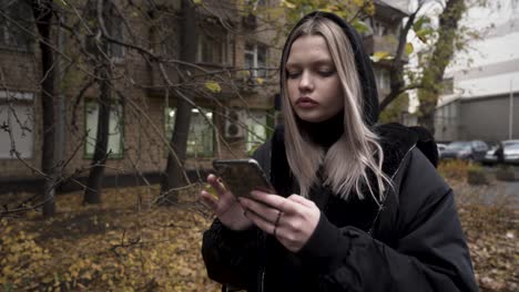 young woman texting on smartphone in autumn city