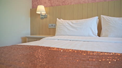 close up bed with pink shiny linen and cushions in hotel room