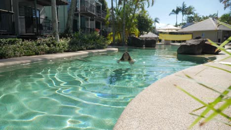 Kaukasische-Frau,-Die-Im-Sommer-Allein-Im-Außenpool-Des-Ferienortes-Schwimmt