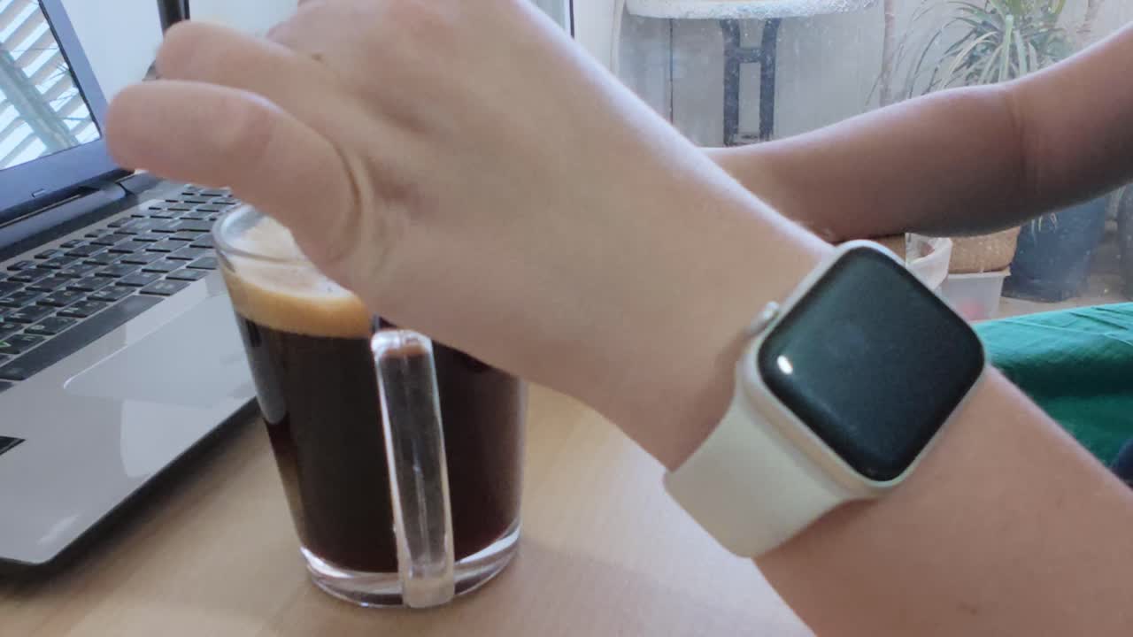 Casual yet productive home office setting. Person using phone with coffee and laptop