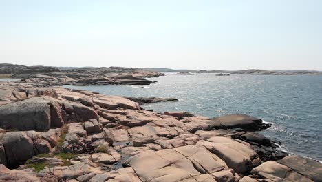 cinematic aerial dolly out shot capturing the beautiful seascape in bohuslan coast and rock shore granite during summer in sweden, low altitude