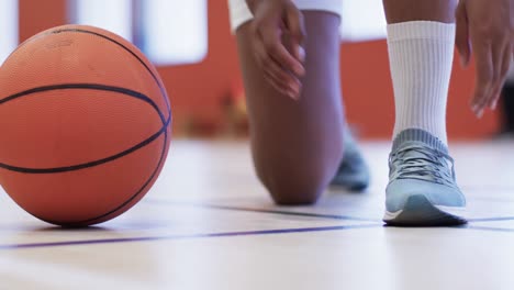jugadora de baloncesto afroamericana ata zapatos en una cancha cubierta, en cámara lenta