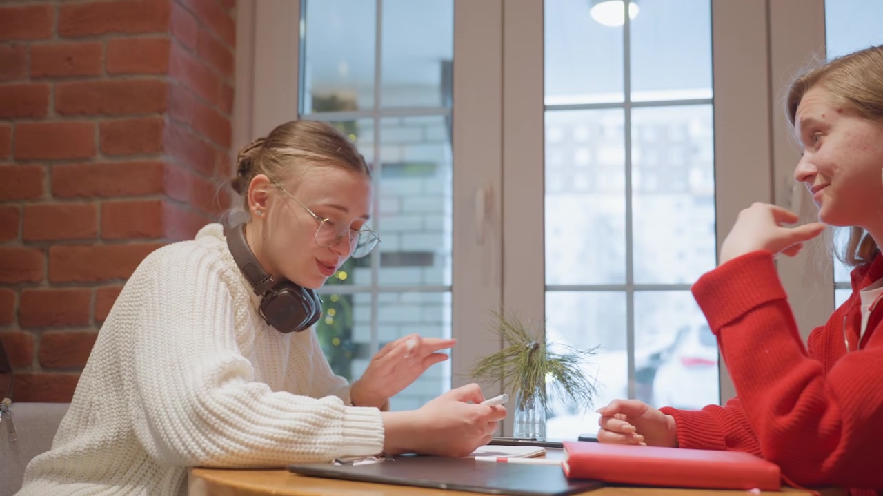Due giovani donne che discutono e prendono appunti a un tavolo di un caffè