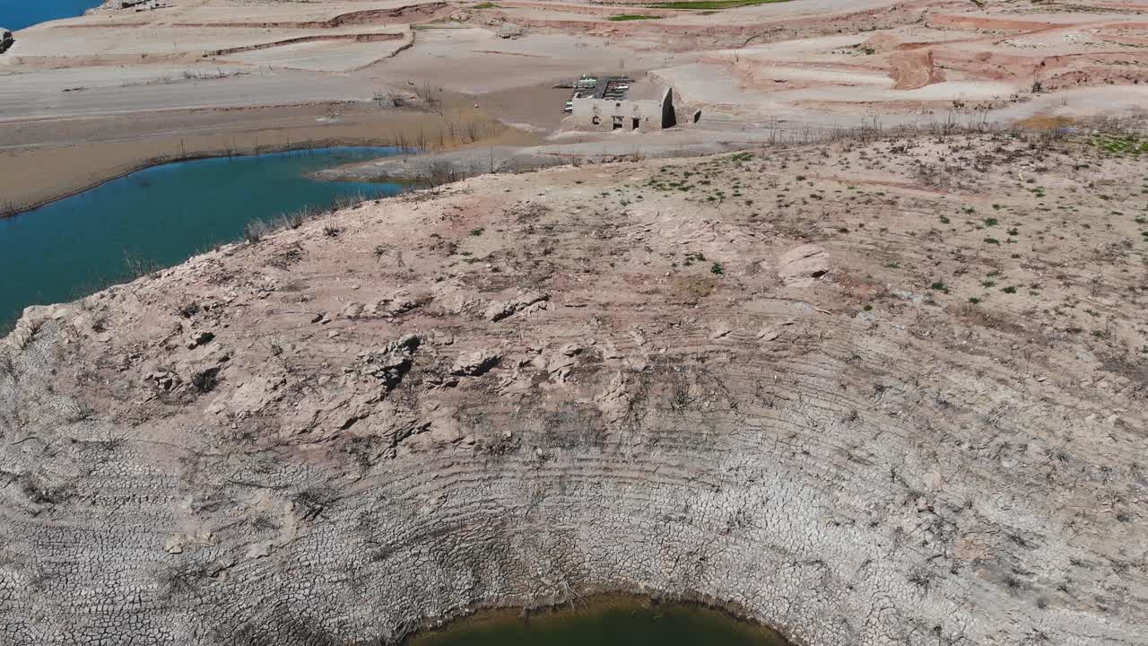 un embalse vacío con casas en ruinas y un muelle vacío