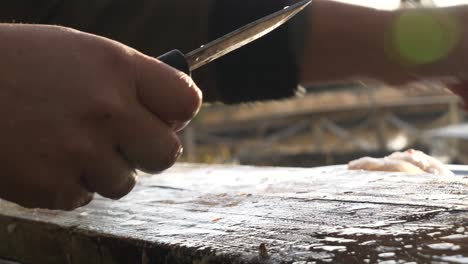 Primer-Plano-De-Manos-Masculinas-Fileteando-Pescado-Fresco-En-La-Mesa-De-Corte-Al-Aire-Libre