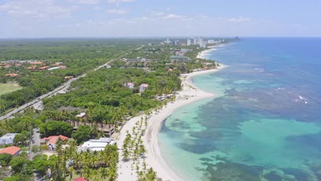 Aerial-backwards-shot-of-beautiful-Juan-Dolio-Beach-with-coral-reefs-underwater-during-sunlight---Tropical-landscape-with-exotic-coastline-on-Dominican-Republic-Island