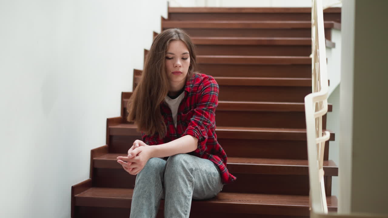 una mujer con emociones negativas se sienta en la escalera. una mujer con problemas de salud mental elige un lugar para estar sola en casa. síntomas del trastorno de depresión