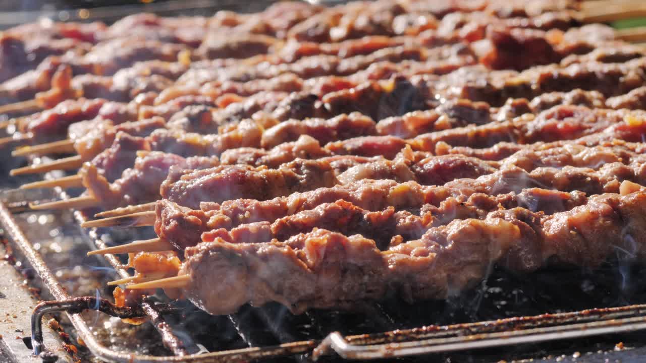 Pork meat skewer on fire, Mutton barbecue close-up. Fried meat for kebab. Cooking grilled meat beef chicken lamb BBQ . Kebab on grill. Chinese street local market with traditional food. Asian fast food.