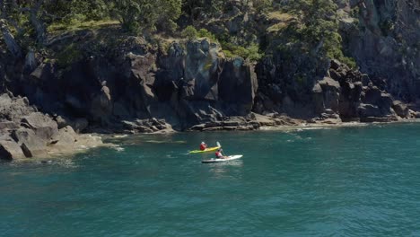 costa escarpada de la isla ballena moutohora con kayakistas remando en aguas tranquilas