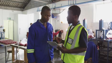 colleagues discussing while using tablet computer in factory