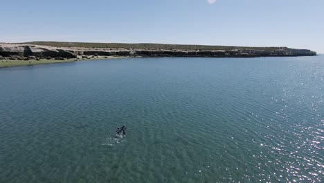 duas pessoas nadando em águas cristalinas azuis profundas perto da costa rochosa durante o dia ensolarado na praia de villarino