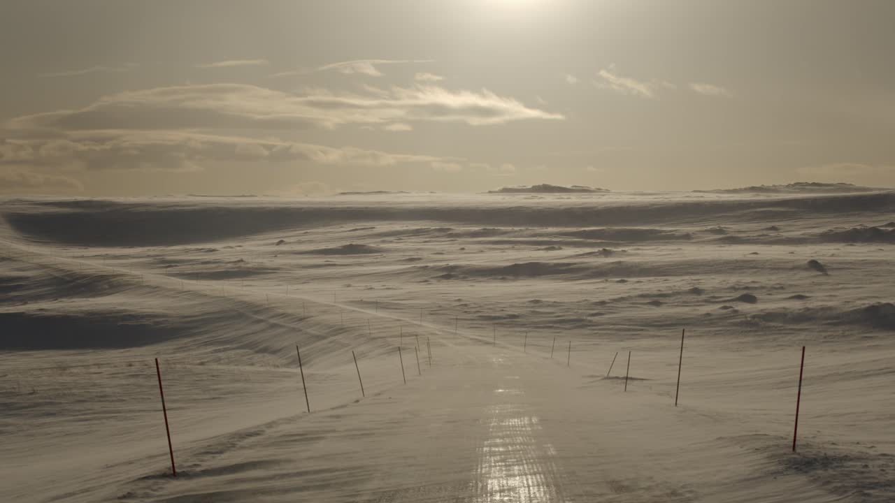 Empty road in a snowstorm at a sunset in the winter in scandinavia