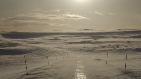 empty road in a snowstorm at a sunset in the winter in scandinavia