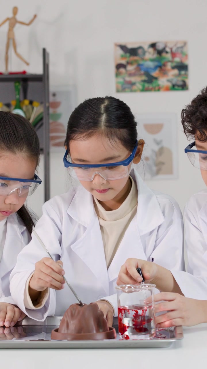 Anak-anak Asia mengenakan jas lab dan kacamata pengaman melakukan percobaan kimia di ruang kelas