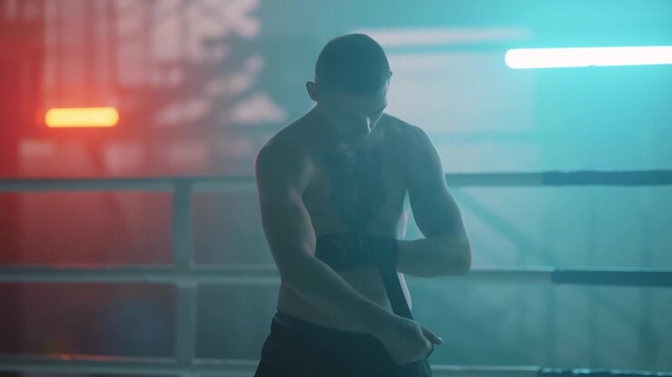 Pugile che si fascia le mani in un ring da boxe suggestivo con luci al neon