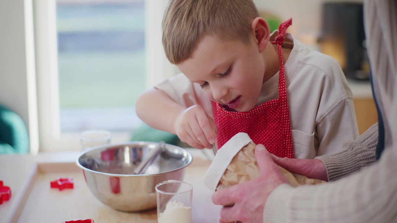 el niño trabaja en la cocina y vierte harina en la masa y la amasa