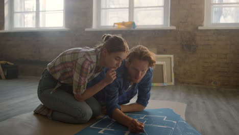 young couple discussing home repair indoors. man drawing on blueprints in house.