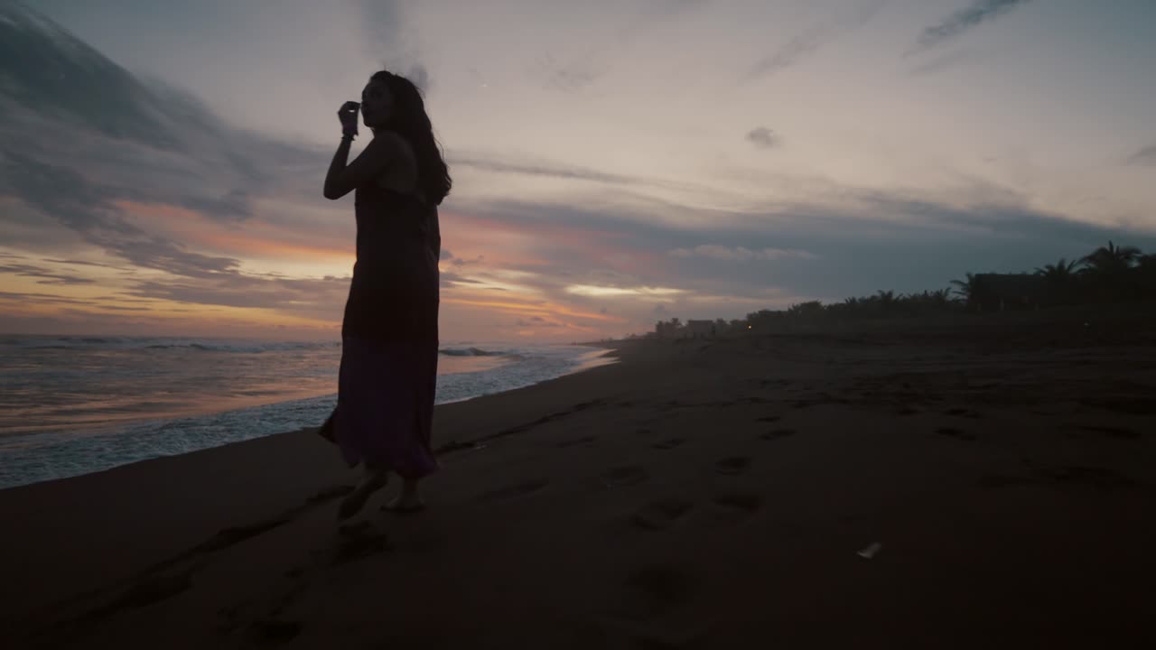 日没時にビーチでドレスを着ている旅行者の女性