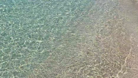 Crystal-clear-transparent-turquoise-water-on-a-white-sand-beach,-small-waves-moving,-summer-dream-vacation-destination-in-Formentera-island-Ses-Illetes-beach-Ibiza-Spain,-4K-static-shot
